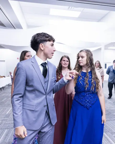 A gentleman in a gray suit leading a lady in a blue gown