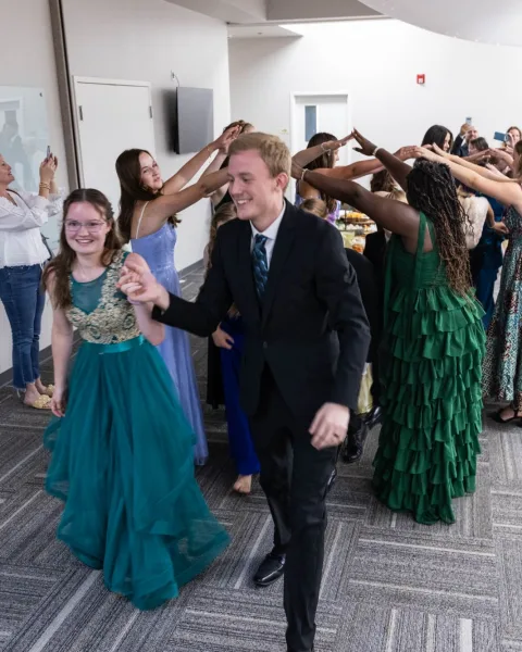 A smiling couple stepping out from under an arch of raised hands